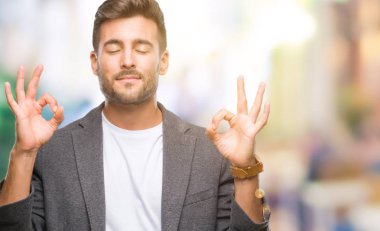 Genç yakışıklı iş adamı izole arka plan üzerinde dinlenmek ve gülümseyen gözlerle kapalı parmak jestle meditasyon yapıyor. Yoga kavramı.