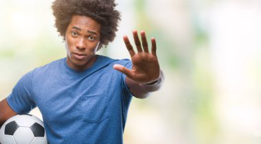 Açık eliyle dur işareti ile ciddi ve kendine güvenen ifade, savunma jest yapıyor izole arka plan üzerinde futbol topu tutan Afro Amerikalı adam