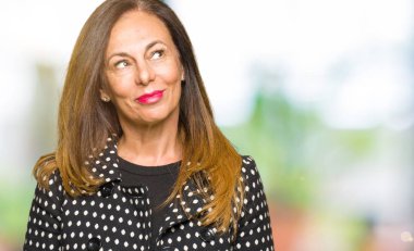 Moda ceket görünümlü yan ve dik dik bakma uzağa düşünce gülümseyen güzel orta yaş kadın.