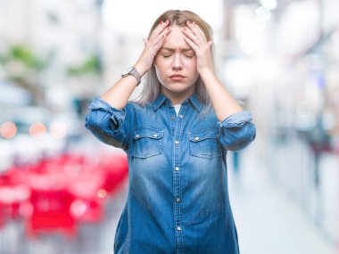 Sarışın, izole edilmiş, baş ağrısı çeken, çaresiz ve stresli genç bir kadın. Ağrı ve migren yüzünden. Ellerini başının üstüne koy..