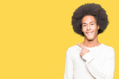 Afro saçlı genç afro-amerikan adam kış kazak neşeli bir yüz yüzü ile işaret eden bir gülümseme ile yan yana mutlu ve doğal ifade ile