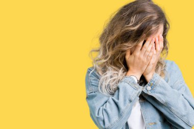 Güzel genç sarışın kadın ağlarken elleri ile yüz kapsayan üzgün ifade ile izole arka plan üzerinde kot ceket giyiyor. Depresyon kavramı.