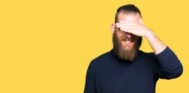 Gözlük ve gülümsüyor ve gözleri için sürpriz kapsayan yüz el ile gülüyor boğazlı kazak giyen genç sarışın adam. Kör kavramı.