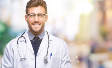 Genç yakışıklı Doktor adam yüzünde mutlu ve güzel bir gülümseme ile izole arka plan üzerinde. Şanslı kişi.