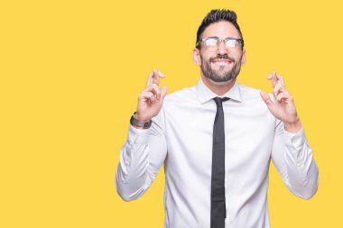 Umut ve gözleri kapalı geçiş parmaklarıyla gülümseyen izole arka plan üzerinde gözlük takan genç yakışıklı iş adamı. Şans ve batıl kavramı.