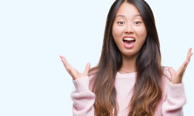 Genç Asyalı kadın deli kutluyor ve silah ile başarı için heyecanlı çığlık kaldırdı ve açık gözleri hayret izole arka plan üzerinde. Kazanan kavramı