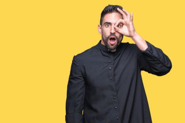 Genç Hıristiyan rahip ok jest sürpriz yüz, göz parmaklarının arasından seyir şok yapıyor izole arka plan üzerinde. İmansız ifade.