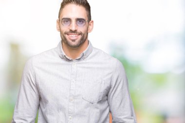 Genç yakışıklı adam yüzünde mutlu ve güzel bir gülümseme ile izole arka plan üzerinde güneş gözlüğü takıyor. Şanslı kişi.