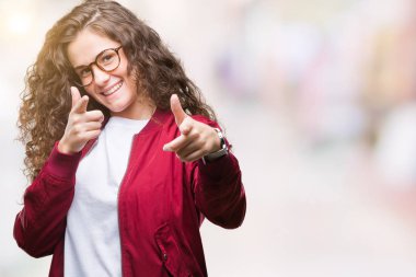 Güzel esmer kıvırcık saçlı Genç kız için fotoğraf makinesi ile mutlu ve komik yüz parmakları işaret izole arka plan üzerinde ceket ve gözlük takıyor. İyi enerji ve vibes.