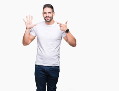 İzole arka plan üzerinde rahat beyaz t-shirt giyen genç adam gösteren ve parmak sayısı yedi ile işaret kadar güven ve mutlu gülümseyen.