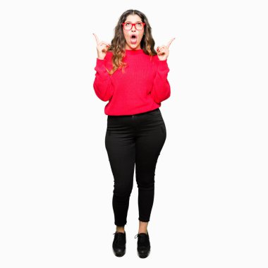 Kırmızı gözlük takan genç güzel kadın hayrete ve yukarıya bakıyor ve parmakları ile işaret ve silah kaldırdı şaşırttı.