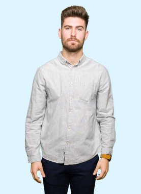 Yüzünde ciddi bir ifade ile rahat gömlek giymiş yakışıklı delikanlı. Basit ve doğal kameraya bakıyor.