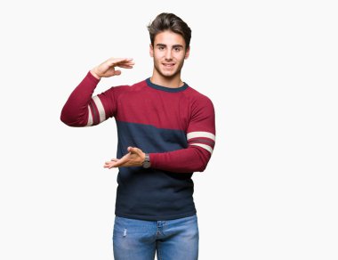 Yakışıklı delikanlı ile büyük ve büyük boy işaret, ölçü birimi sembol gösteren el eller izole arka plan üzerinde. Kameraya bakarak gülümsüyordu. Ölçüm kavramı.