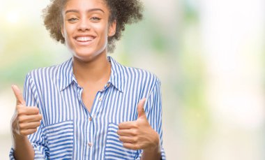 İzole arka plan başarı işareti el ile olumlu hareketi yaparken Genç afro Amerikan kadın başparmak gülümseyen ve mutlu. Neşeli bir ifadeyle, kazanan jest kameraya bakıyor.