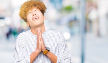 Şık gömlek yalvarıyor ve umut ifade yüzünde çok duygusal ve endişe ile birlikte elleriyle dua afro saçlı Genç yakışıklı iş adamı. Bağışlanmak. Din kavramı.