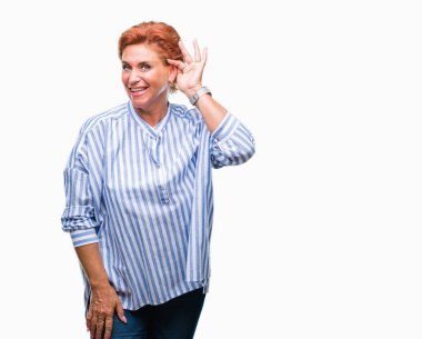 Atrractive üst düzey beyaz Kızıl saçlı kadın bir işitme söylenti ya da dedikodu için dinleme kulak üzerinde el ile gülümseyen izole arka plan yüzünden. Sağırlık kavramı.