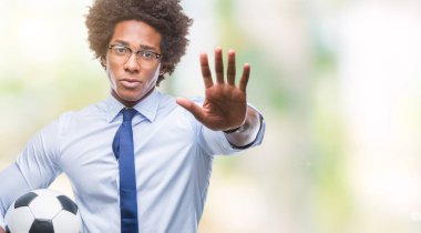 Açık eliyle dur işareti ile ciddi ve kendine güvenen ifade, savunma jest yapıyor izole arka plan üzerinde futbol topu tutan Afro Amerikan Yöneticisi adam