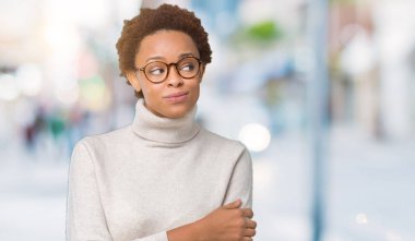 Genç güzel Afrikalı-Amerikalı kadın görünümlü yan ve dik dik bakma uzağa düşünce gülümseyen izole arka plan üzerinde gözlük.