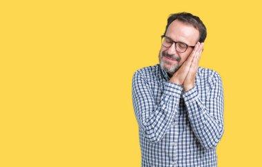 Uyku yorgun hayal ve ellerle birlikte poz ile kapalı gözler gülümseyen izole arka plan üzerinde gözlük takan yakışıklı orta yaş zarif üst düzey iş adamı.