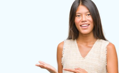 Genç Asyalı kadın üzerinden hayran ve el ile sunulması ve parmak ile işaret ederken kameraya gülümseyen izole arka plan.