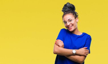 Genç saç Afro-Amerikan kız mutlu yüz ile gülümseyerek kameraya seyir silah geçti izole arka plan üzerinde gözlük takan örgülü. Olumlu bir kişi.