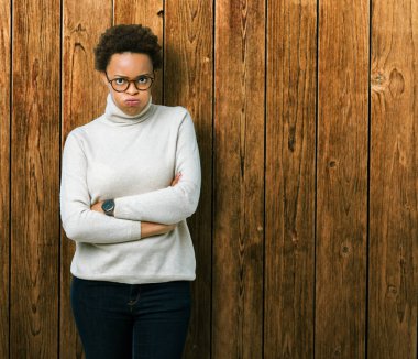 İzole arka plan şüpheci ve çapraz kolları olan yüzündeki gergin, onaylamayan ifade gözlüklü genç güzel Afrikalı-Amerikalı kadın. Negatif kişi.