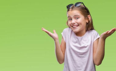 Genç güzel kız izole arka plan clueless ve şaşkın bir ifadeyle kollar ve eller kaldırdı üzerinde güneş gözlüğü takıyor. Şüphe kavramı.