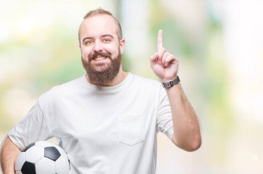 Futbol futbol topu izole arka plan üzerinde bir fikir ya da soru işaret parmağı gülen yüz, bir numara ile sürpriz tutan genç beyaz hipster adam
