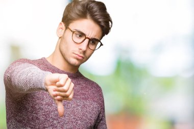 Mutsuz ve kızgın ret gösterilen ve başparmak aşağı hareketi ile negatif seyir izole arka plan üzerinde gözlük takan yakışıklı delikanlı. Kötü ifade.