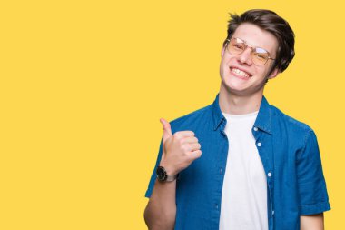 Gülümseyen, parmakları ile mutlu yüz üzerinden seyir göz el ile ok jest yapıyor izole arka plan üzerinde gözlük takan genç yakışıklı adam.