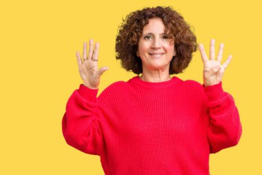 Güzel orta ager kadın kıdemli kırmızı kış kazak üzerinde gösterilen arka plan izole ve parmakları ile işaret numara 9 kendinden emin ve mutlu gülümseyerek süre.