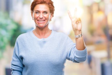 Mutlu yüz zafer işareti yaparken kameraya göz kırpıyor ile gülümseyen izole arka plan Atrractive üst düzey beyaz Kızıl saçlı kadın. İki numaralı.