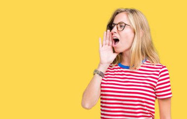 Bağırarak ve ağzı üzerinde el ile yan için çığlık izole arka plan üzerinde gözlük güzel ve genç birbayan. İletişim kavramı.