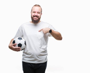 Sürpriz yüz işaret parmağı kendini izole arka plan üzerinde futbol futbol topu tutan genç beyaz hipster adam
