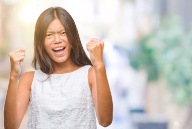 Gülümseyen ve başarı için çığlık Genç Asyalı kadın izole arka plan çok mutlu ve heyecanlı kaldırdı, silah ile kazanan jest yapıyor. Kutlama kavramı.