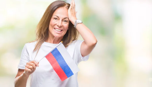 Middle age hispanic woman holding flag of Russia over isolated background stressed with hand on head, shocked with shame and surprise face, angry and frustrated. Fear and upset for mistake.
