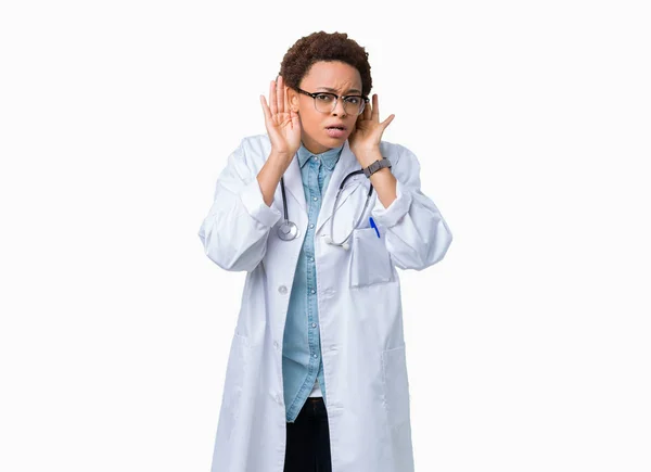 年轻的非洲美国医生妇女穿着医疗外套在孤立的背景试图听到双手对耳朵的手势 好奇八卦 听力问题 — 图库照片