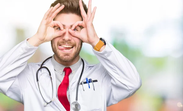 Young Handsome Doctor Man Wearing Medical Coat Doing Gesture Binoculars — Stock Photo, Image