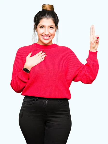 赤いセーターとパンを胸と指に手で誓う若い美しい女性 忠誠の誓いを立てる — ストック写真