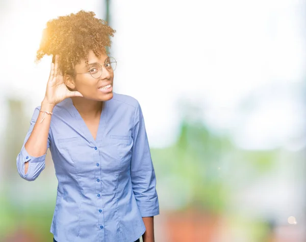 Beautiful young african american business woman over isolated background smiling with hand over ear listening an hearing to rumor or gossip. Deafness concept.