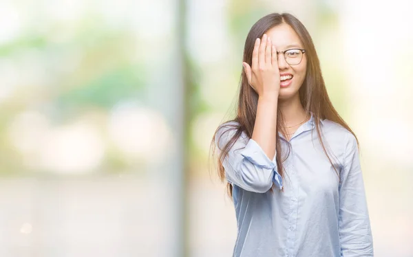 年轻的亚洲女商人戴眼镜在孤立的背景覆盖一只眼睛用手自信的笑容和惊喜的情感 — 图库照片