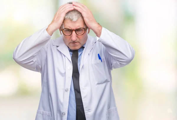 Handsome senior doctor, scientist professional man wearing white coat over isolated background suffering from headache desperate and stressed because pain and migraine. Hands on head.