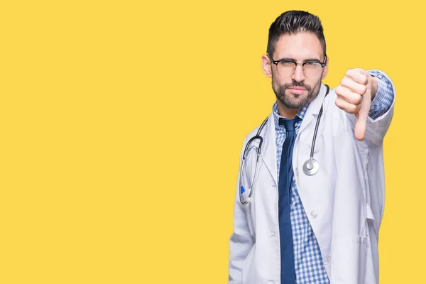 Handsome young doctor man over isolated background looking unhappy and angry showing rejection and negative with thumbs down gesture. Bad expression.