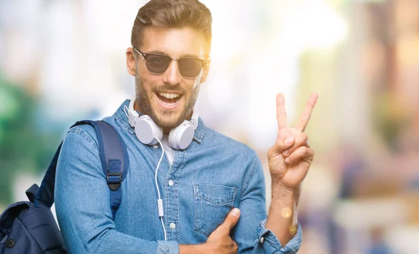 Junger Gutaussehender Touristenmann Mit Kopfhörern Und Rucksack Vor Isoliertem Hintergrund — Stockfoto