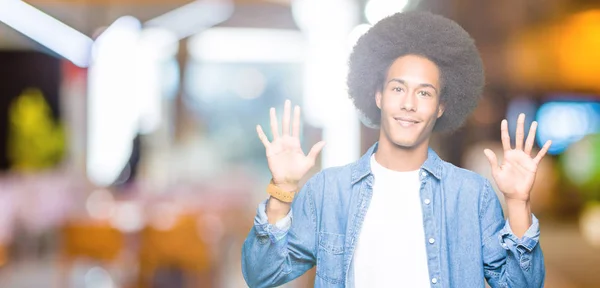 アフロの髪を指で上向きの表示と若いアフリカ系アメリカ人は自信を持って 幸せな笑みを浮かべている間 番号します — ストック写真
