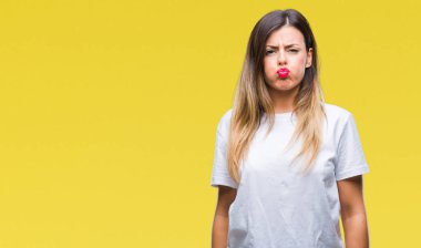 Genç güzel kadın izole arka plan şişirme üzerinde rahat beyaz t-shirt ile komik surat yanakları. Ağız ile hava, deli ifade şişirilmiş.