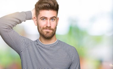 Genç yakışıklı kazak şaşırtmak ve soru hakkında merak ediyorum giyen çizgili adam. Şüphe, kafasına el ile düşünme ile belirsiz. Dalgın kavramı.