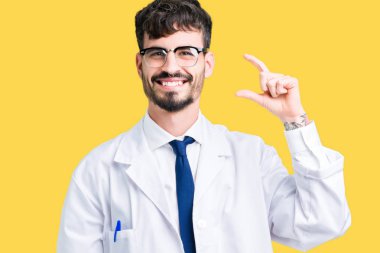 İzole arka plan gülümseyen ve boyutu işaret parmaklı ararken ve kamera işi el ile kendinden emin eller üzerinde beyaz önlük giyen genç profesyonel bilim adam. Ölçü kavramı.
