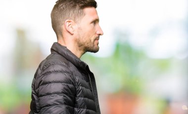 Yakışıklı adam giyen kış ceket tarafına, seyir dinlenmek doğal yüz emin gülümseme ile pozuyla profili.