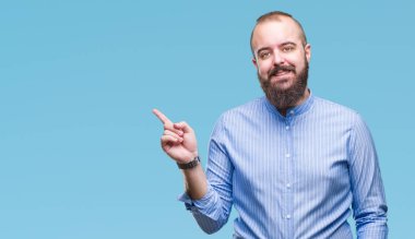 Kameraya bakarak yan el ve parmak ile işaret eden genç beyaz hipster adam yüzünde kocaman bir gülümseme ile izole arka plan üzerinde.